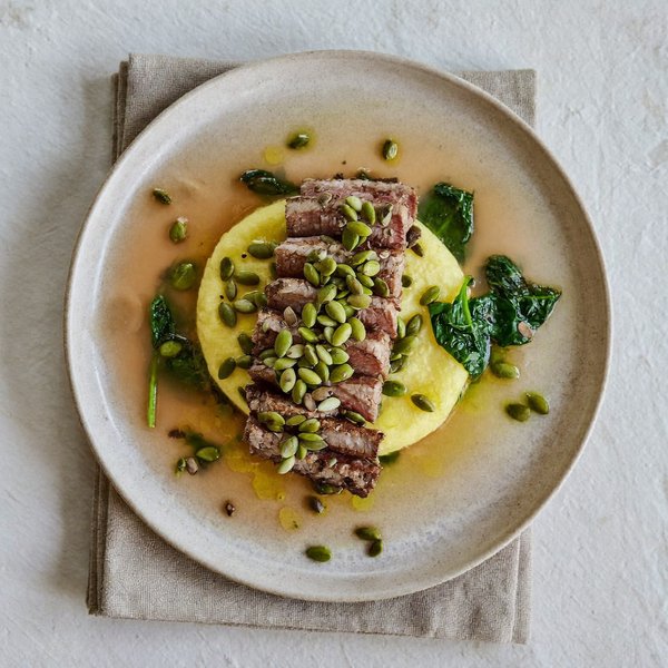 Res con Costra de Semillas de Calabaza sobre Polenta Suave con Espinacas Marchitas