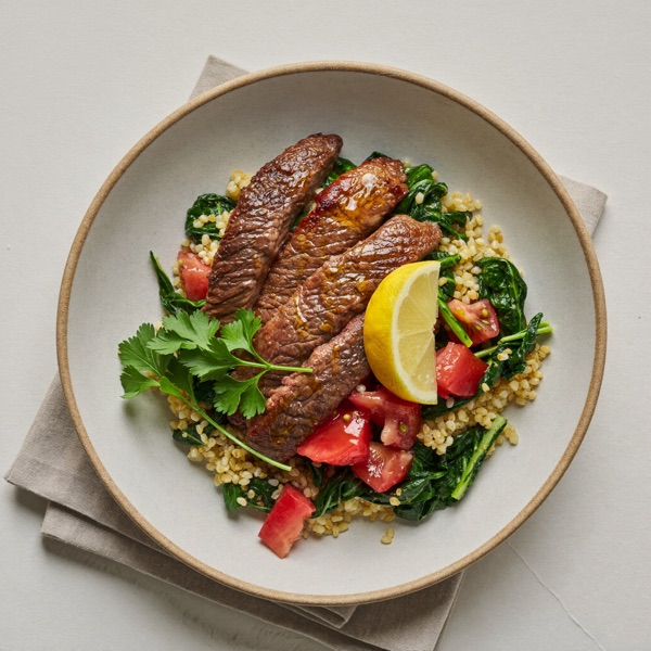 Getreidebowl mit magerem Rindfleisch, Spinat und Tomate